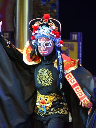 A mask changing performer in a painted Sichuan opera mask