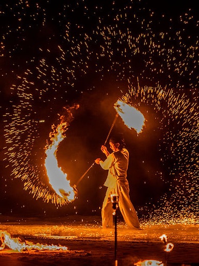 A fire show performer spinning fire in a shower of sparks