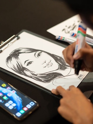 A caricature artist drawing a guest&rsquo;s portrait by hand