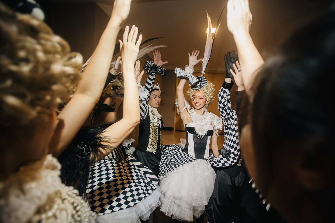 Ballet dancers in harlequin costumes performing among the guests