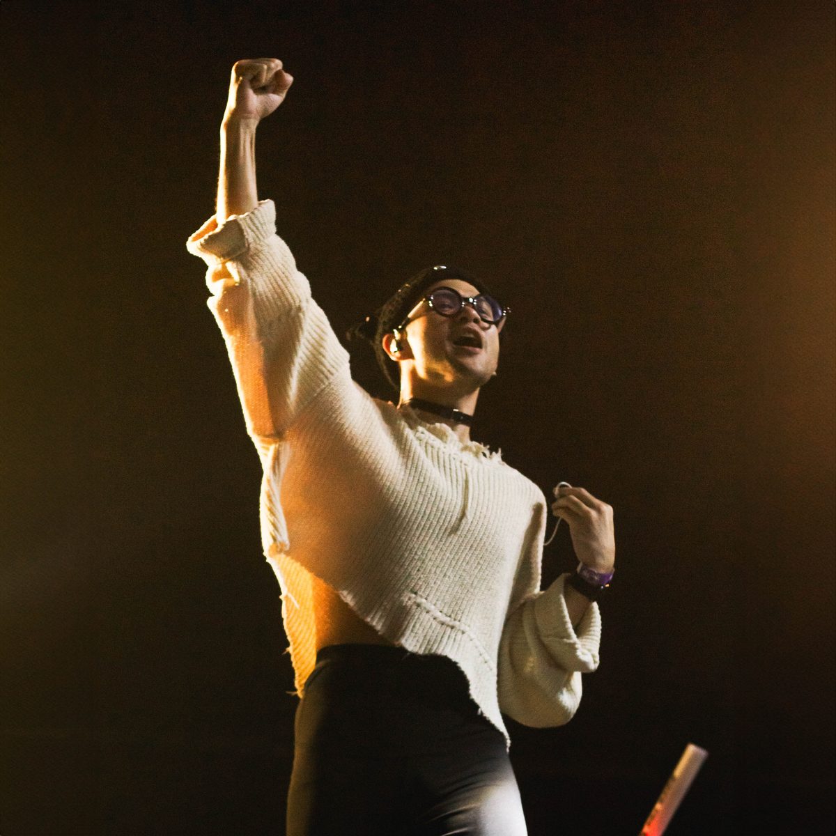A modern orchestra performer on stage, one fist raised