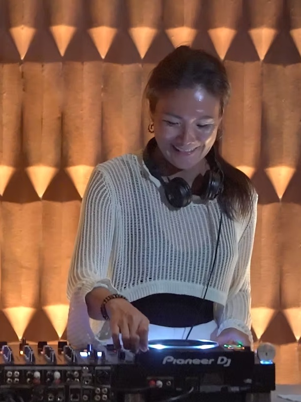 A DJ in headphones playing a set at the decks