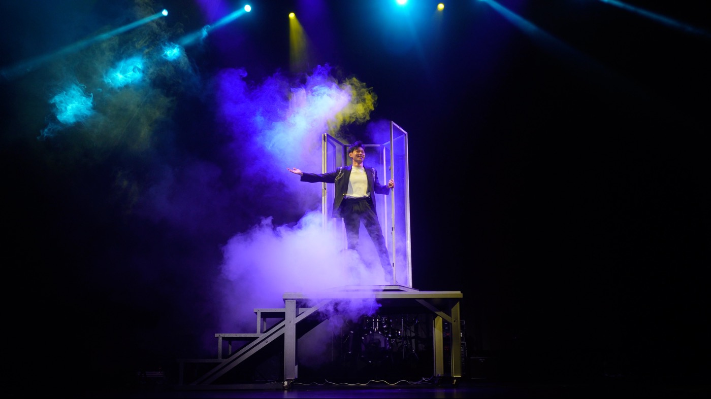A magician appearing in a glass chamber in a cloud of smoke
